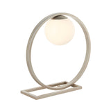 Brackstead Table Lamp in brushed silver, a circular metal frame on a rectangular base holding a lit opal glass sphere, shown on a plain white background.