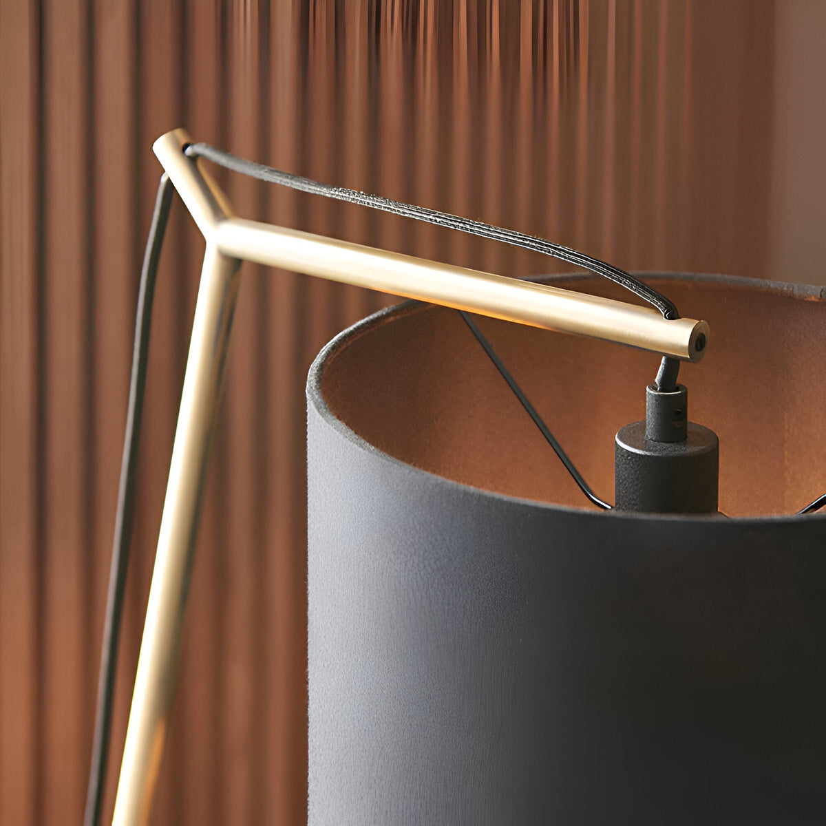 Close-up of the Endon Carlfield table lamp showing the matt brass cantilevered arm meeting the black cotton shade against a warm ribbed backdrop.