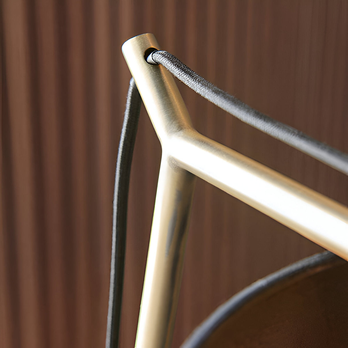 Close-up of the Endon Carlfield table lamp showing the matt brass cantilevered arm joint and black fabric flex against a wood-panelled backdrop.