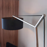 Carlfield Floor Lamp in matt nickel, close-up of angled metal arm and joint with black cord, cylindrical black fabric shade visible against a light wall.