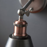 Close-up of the Endon Brackley wall light showing the aged copper lamp holder, knurled rings, adjustable pewter head joint with wing screw, and metal shade.