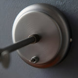 Close-up of the Endon Brackley wall light backplate in aged pewter, showing the knurled arm fixing and toggle on/off switch against a grey wall.
