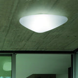 Stone LED Flush Ceiling Light in white, an asymmetric pebble-shaped diffuser glowing on an exposed concrete ceiling above a glazed interior doorway.