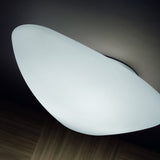 Stone LED Flush Ceiling Light in white, pebble-shaped diffuser mounted flush to a dark ceiling, glowing softly above a wooden floor.