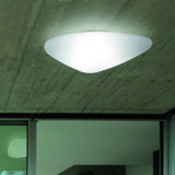 Stone LED Outdoor Flush Ceiling Light in white, pebble-shaped diffuser glowing on a concrete ceiling above a glazed interior doorway.