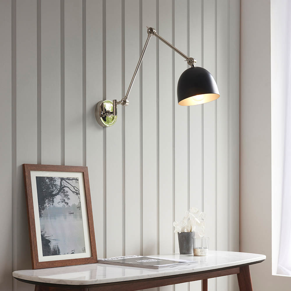 Endon Caldhurst adjustable wall light with polished nickel jointed arm and matt black dome shade, mounted above a marble console with framed print.