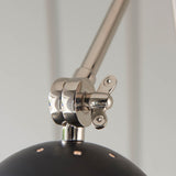 Close-up of the Endon Caldhurst wall light's polished nickel adjustable joint with knurled detail, above the matt black shade.