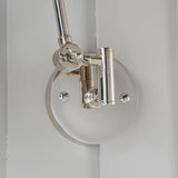 Close-up of Endon Caldhurst wall light mounting, showing polished nickel adjustable joint and round backplate with visible fixing screws against a pale wall.