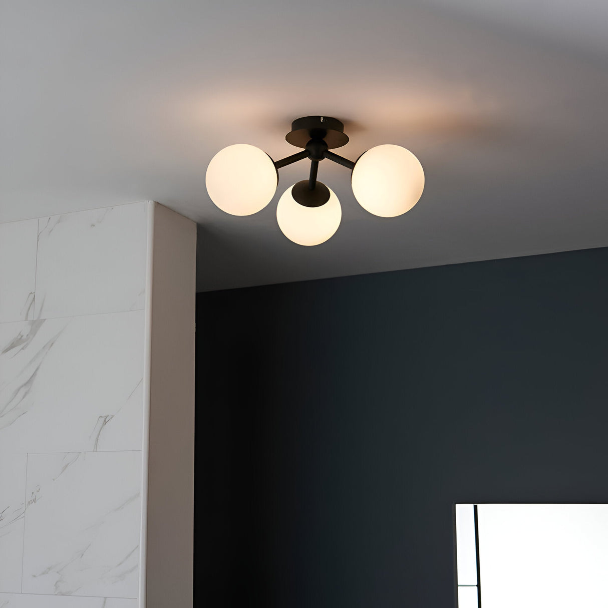 Endon Marden 3-light semi-flush bathroom ceiling light in matt black with three opal glass globes, mounted to a white ceiling beside a dark wall.