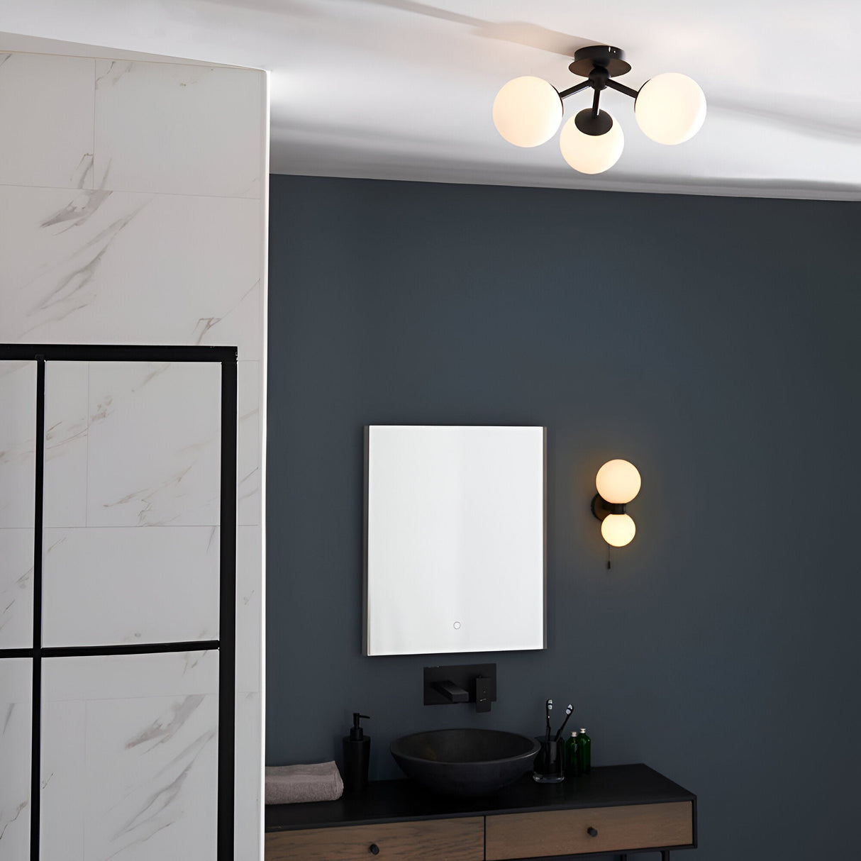 Endon Marden semi-flush ceiling light with three opal glass globes on matt black arms, installed in a modern bathroom with matching wall light and mirror.