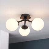 Endon Marden semi-flush bathroom ceiling light with three opal glass globes on matt black arms, mounted to a white ceiling in a modern interior.