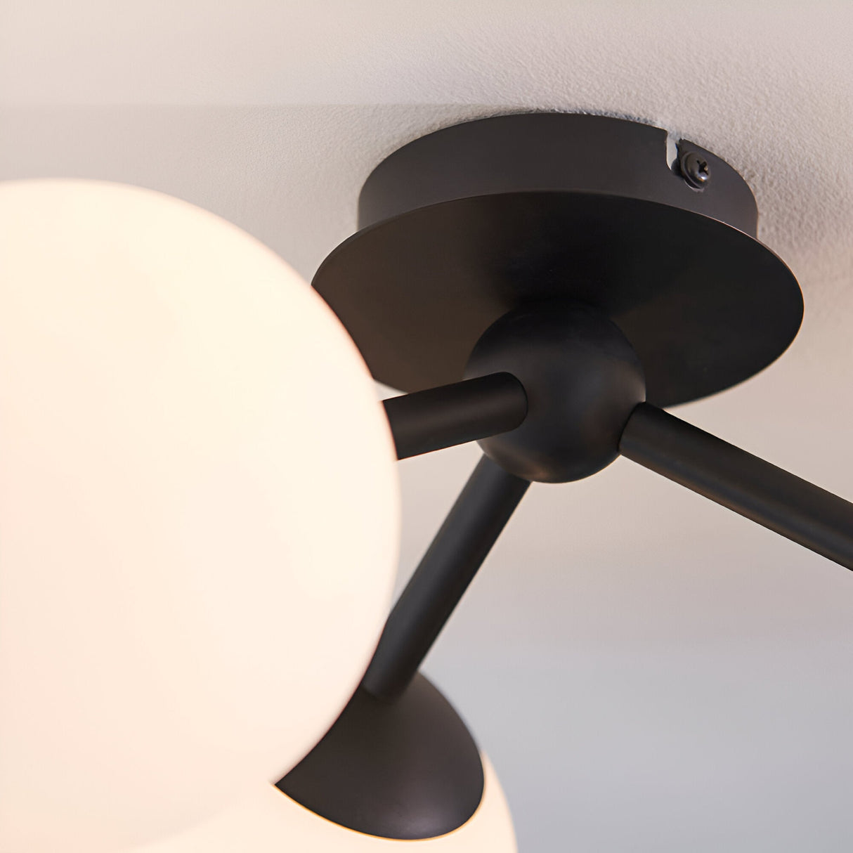 Close-up of the Endon Marden semi-flush bathroom ceiling light showing its matt black steel ceiling plate, arms, and opal glass globe shade.