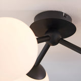 Close-up of the Endon Marden semi-flush bathroom ceiling light showing its matt black steel ceiling plate, arms, and opal glass globe shade.