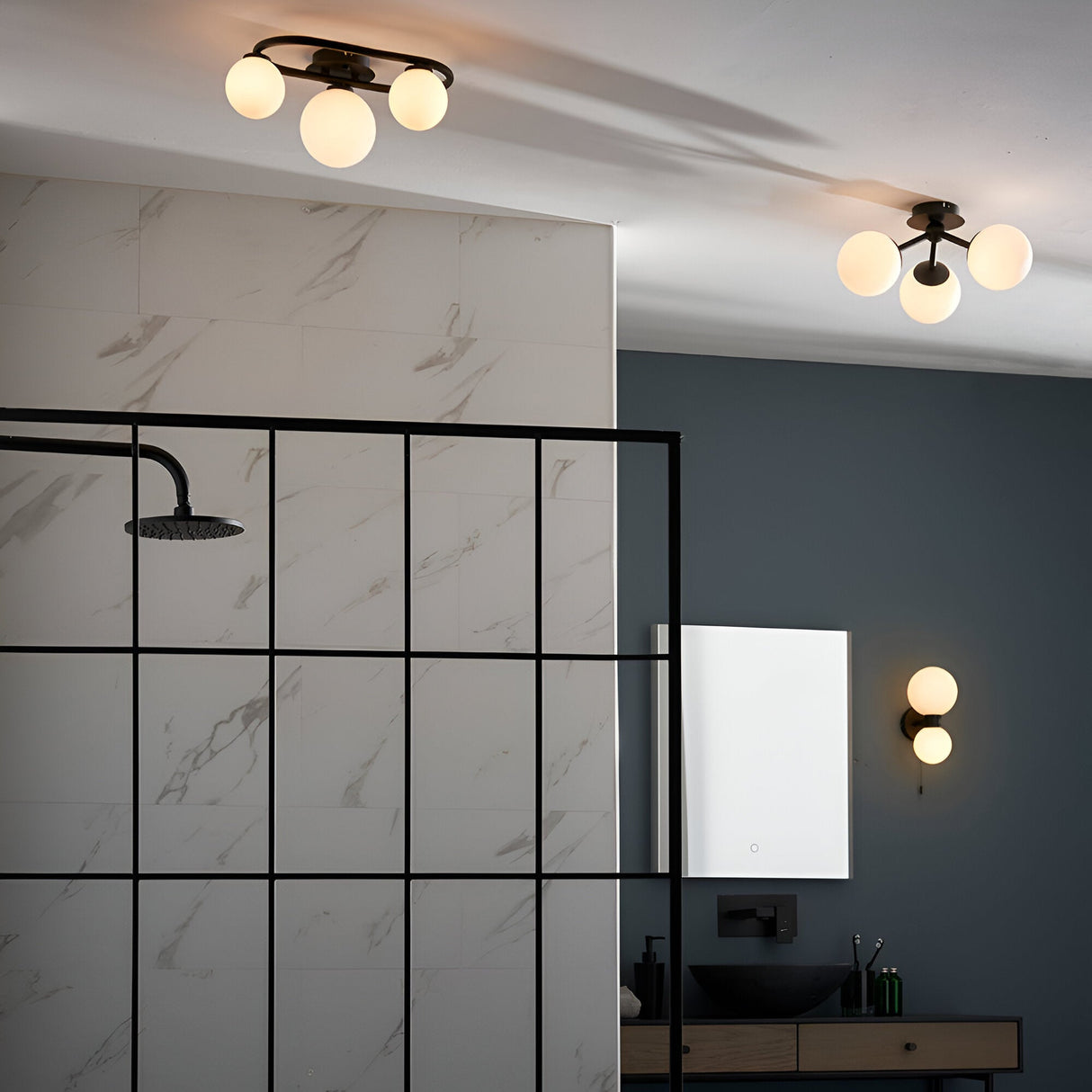 Endon Marden matt black semi-flush bathroom ceiling light with three glass globe shades on an oval steel frame, shown in a modern bathroom.