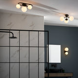 Endon Marden matt black semi-flush bathroom ceiling light with three glass globe shades on an oval steel frame, shown in a modern bathroom.