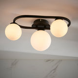 Endon Marden 3 light oval semi-flush bathroom ceiling light in matt black, with three opal glass globe shades on a steel frame mounted to a white ceiling.
