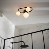 Endon Marden semi-flush bathroom ceiling light in matt black with three opal glass globes set in an oval steel frame, above a marble-tiled shower.