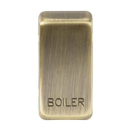 The product is a "Marked BOILER" switch cover in Antique Brass, featuring the word 'BOILER' engraved on it. It has a brushed metal texture that provides a vintage or industrial look. This rectangular cover with rounded edges gives off a classic rocker switch vibe for an elegant and timeless appeal.