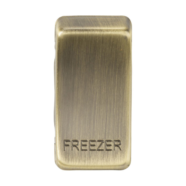 A switch cover in antique brass, known as "Marked FREEZER," features a brushed texture and displays the word FREEZER in engraved capital letters, reminiscent of classic rocker covers.