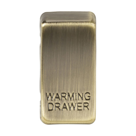 Close-up of the Switch Cover "Marked WARMING DRAWER" in antique brass, showcasing embossed lettering and interchangeable rocker covers.