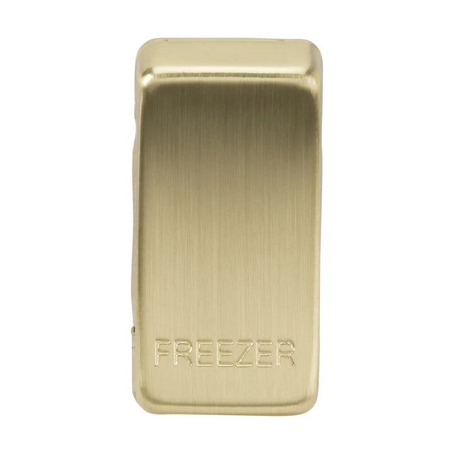 Displayed is the Switch Cover "Marked FREEZER" in brushed brass, featuring a magnetic clip with a smooth metallic surface and the word FREEZER engraved on it. It is designed to securely hold items such as bags closed.