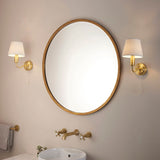 Endon Bevton bathroom wall lights in satin brass with ivory fabric shades and pull cords, mounted either side of a round brass mirror above a basin.