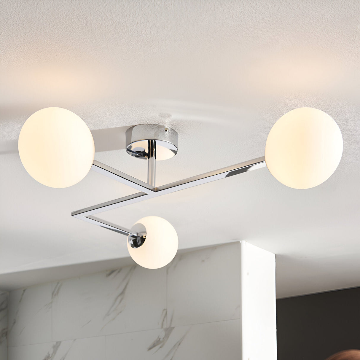 Kelham 3 Light Semi-Flush Bathroom Ceiling Light in chrome, with angular arms and three round opal glass globes, shown fitted to a white ceiling.