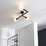 Endon Kelham 3 Light semi-flush bathroom ceiling light in black with three opal glass globes on angular arms, mounted to a white ceiling above marble tiling.