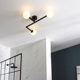 Endon Kelham 3 light semi-flush bathroom ceiling light in black with angular arms and three white glass globes, mounted above a marble-tiled shower.
