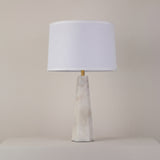 Orix Alabaster Pillar Table Lamp with a tapered faceted natural alabaster column, brushed brass collar, and soft white tapered drum shade on a plain background.