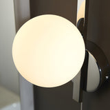 Endon Kelham bathroom wall light with a single matt opal glass sphere held within a polished chrome geometric frame, illuminated.