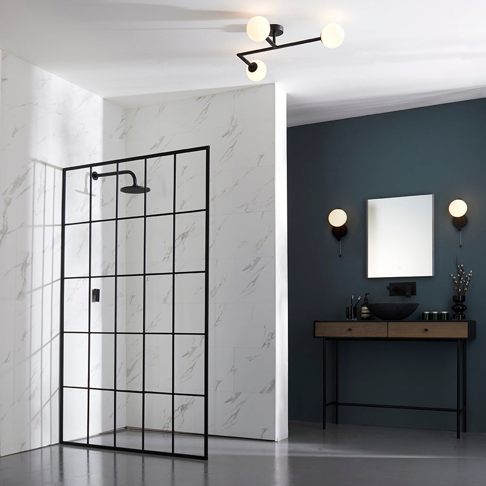 Kelham Bathroom Wall Light in black, single opal glass globe with pull cord, shown either side of a mirror in a dark bathroom setting.