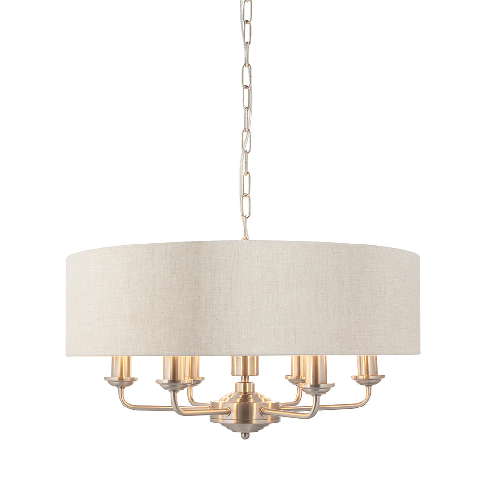 Brenley 6-light pendant with a round linen drum shade and six candle-style arms in brushed nickel finish, hung on a chain, shown on a plain white background.