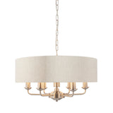 Brenley 6-light pendant with a round linen drum shade and six candle-style arms in brushed nickel finish, hung on a chain, shown on a plain white background.