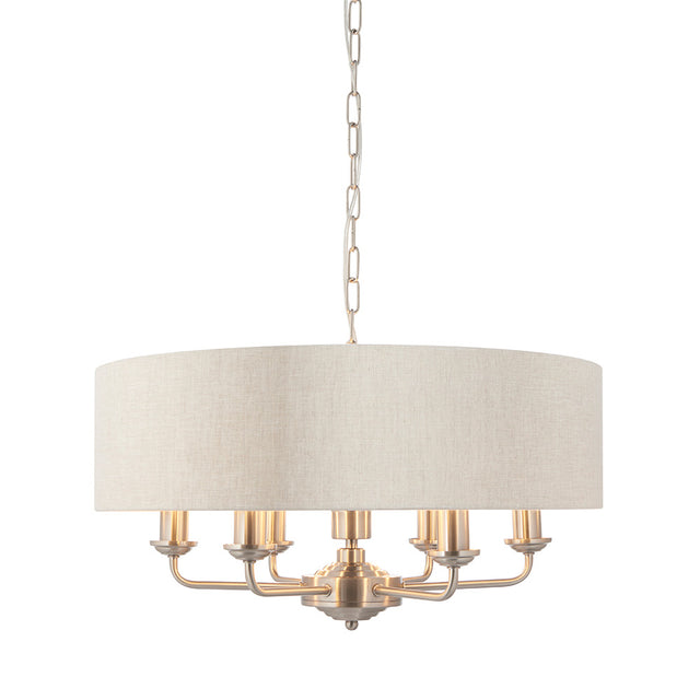 Brenley 6-light pendant with a round linen drum shade and six candle-style arms in brushed nickel finish, hung on a chain, shown on a plain white background.