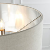 Close-up of the Brenley 3 Light Floor Lamp's natural linen shade with reflective inner lining, showing an E14 candle bulb on brushed chrome metalwork.