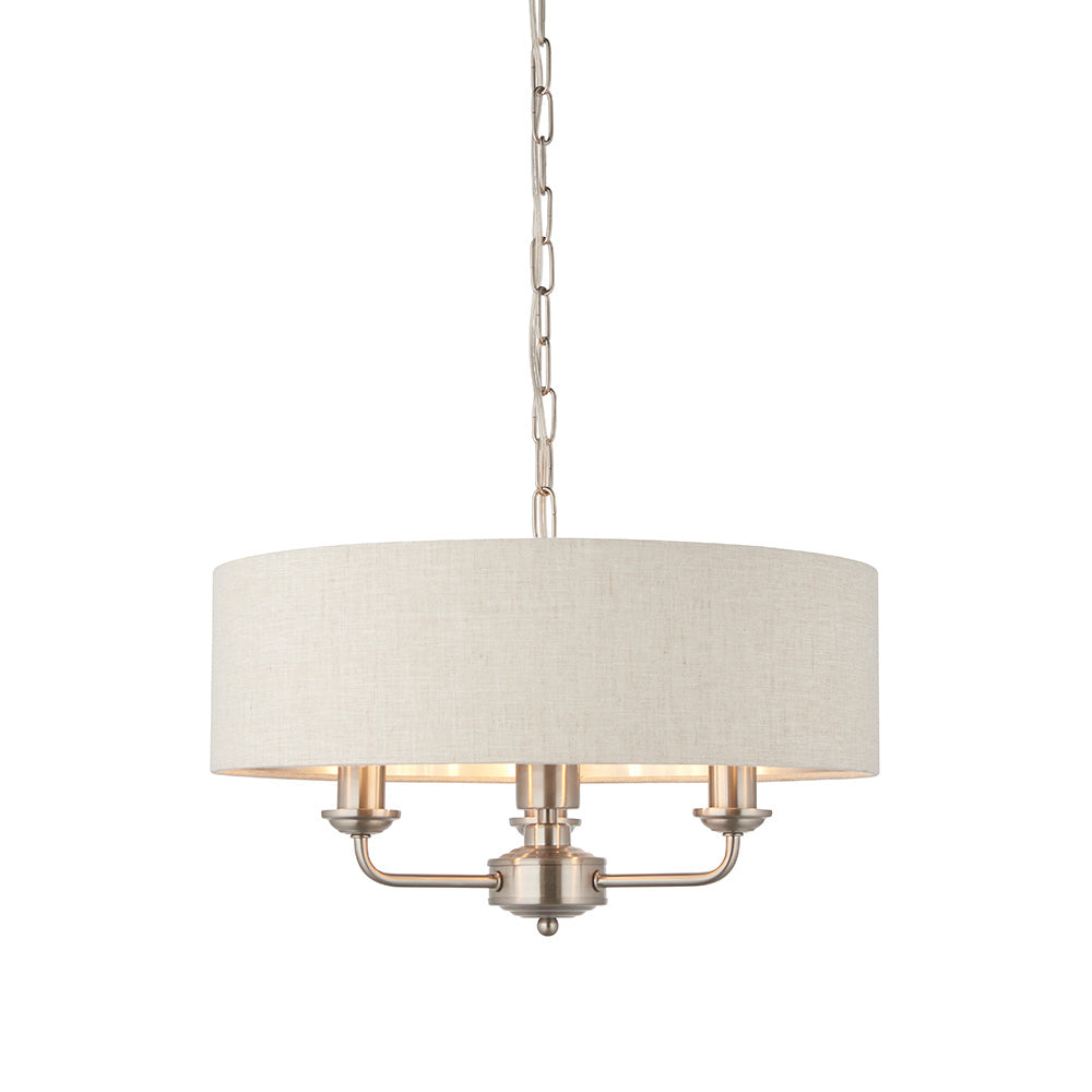 Brenley 3-Light Pendant with round linen drum shade, brushed nickel finish, three candle-style bulb holders, and chain suspension on a white background.