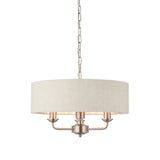 Brenley 3-Light Pendant with round linen drum shade, brushed nickel finish, three candle-style bulb holders, and chain suspension on a white background.