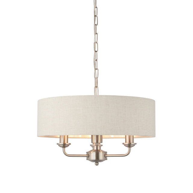 Brenley 3-Light Pendant with round linen drum shade, brushed nickel finish, three candle-style bulb holders, and chain suspension on a white background.