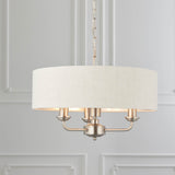 Brenley 3-Light Pendant with white linen drum shade, brushed metallic lining, chrome fittings, and three exposed candle-style arms on a chain.