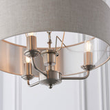 Brenley 3 Light Pendant close-up showing chrome candle-style arms with E14 bulbs beneath a grey linen drum shade with reflective inner lining.