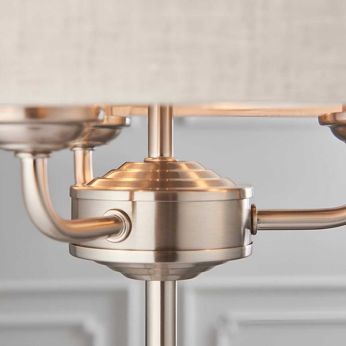 Close-up of the Endon Brenley 3 Light Table Lamp showing brushed chrome centre hub, curved arms and central stem beneath a natural linen shade.
