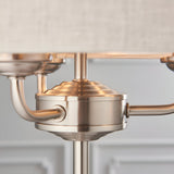 Close-up of the Endon Brenley 3 Light Table Lamp showing brushed chrome centre hub, curved arms and central stem beneath a natural linen shade.