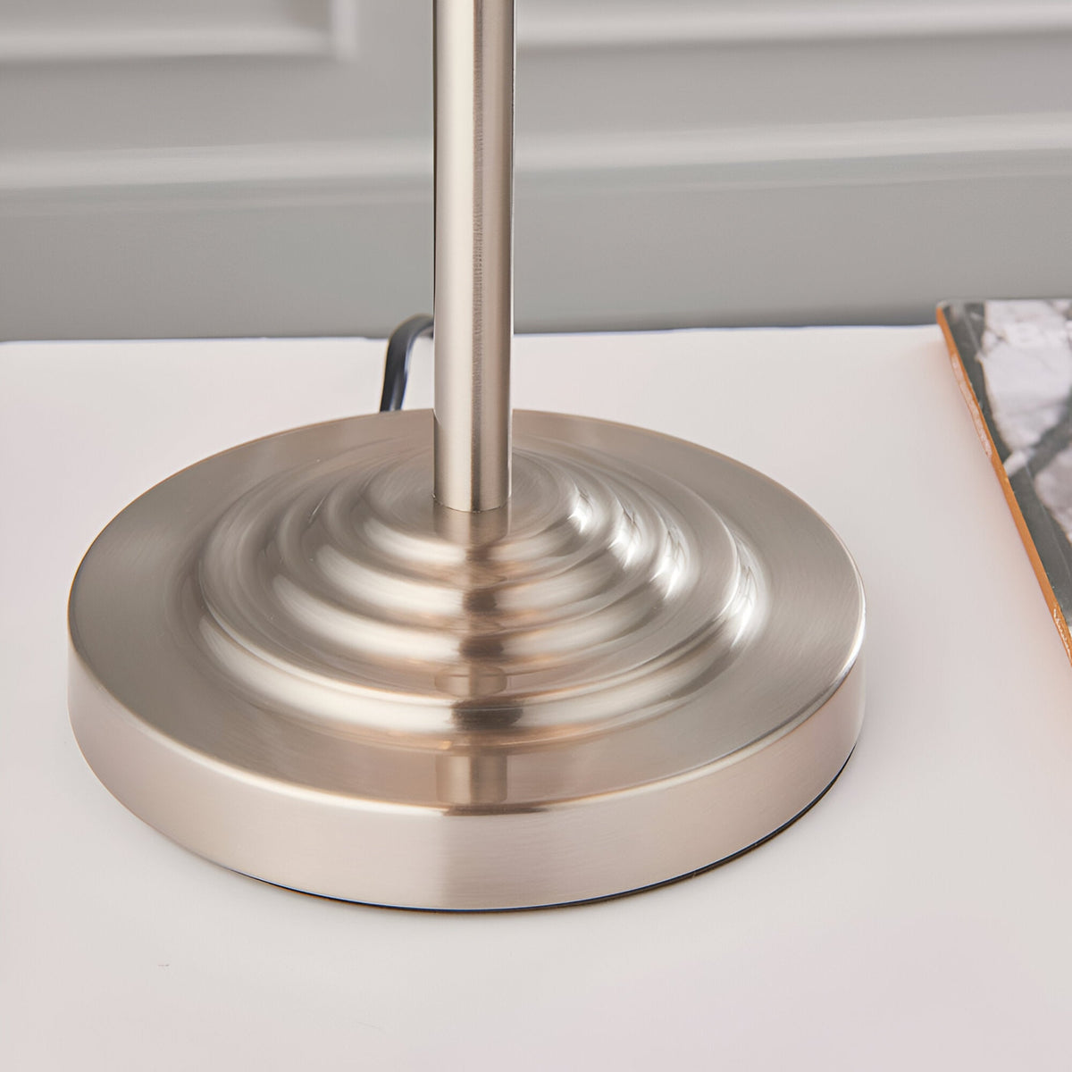 Close-up of the brushed chrome circular tiered base of the Endon Brenley 3 Light Table Lamp on a white surface.