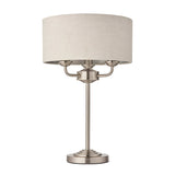 Endon Brenley 3 light table lamp with brushed chrome metalwork, slim stem, and natural linen drum shade, shown on a plain white background.