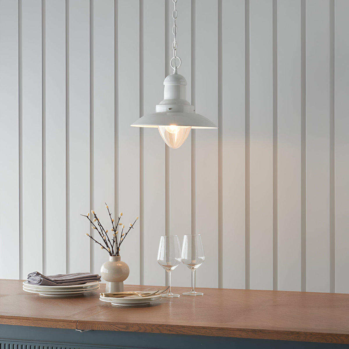 Endon Chartford cream gloss pendant light with shaped clear glass shade and chain suspension, hung above a wooden countertop against panelled walls.