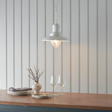 Endon Chartford cream gloss pendant light with shaped clear glass shade and chain suspension, hung above a wooden countertop against panelled walls.
