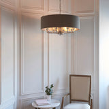 Endon Brenley V2 6 Light Pendant in nickel with charcoal drum shade, hanging from a chain above a marble side table and chair in a panelled room.