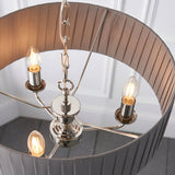 Brenley V2 3 Light Pendant in nickel, showing three candle-style E14 bulbs on metal arms beneath a pleated grey fabric shade with mirrored inner lining.