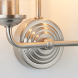 Close-up of the Brenley 2 Light Wall Light's chrome backplate with ribbed detailing and brass arm, showing the joint where the metal fittings connect.